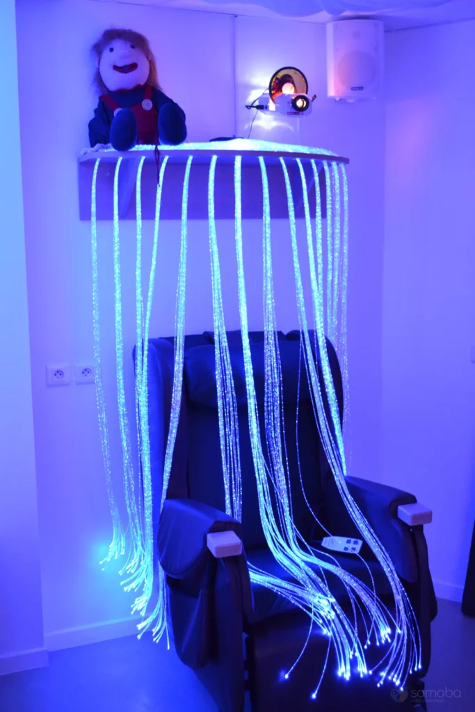 cascade de fibre optique tombant sur fauteuil avec peluche et vidéo projecteur 