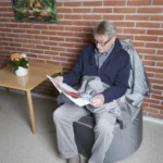 homme âgée, calme, lis le journal, fauteuil